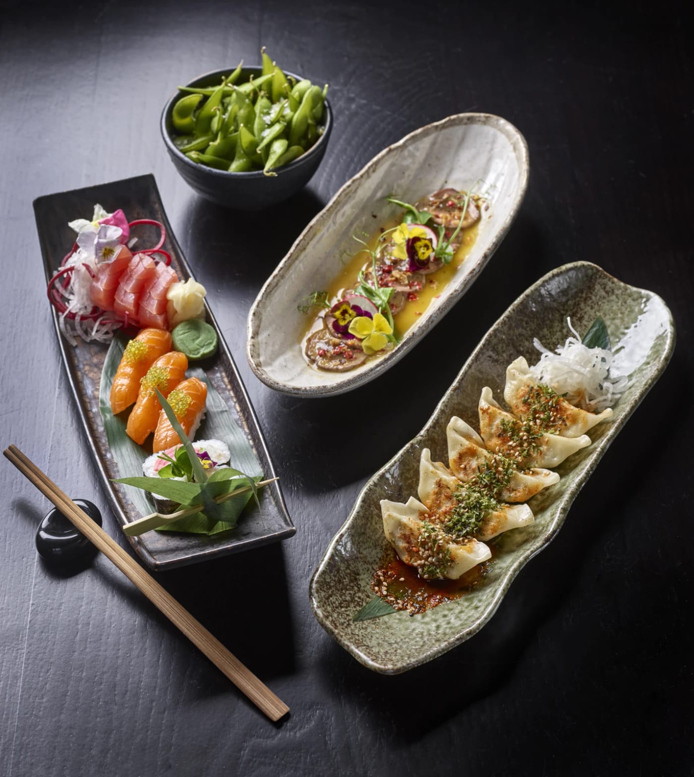 Sushi rolls and gyoza served in wooden boats