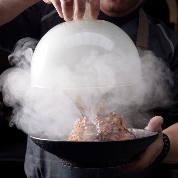 A glass cloche lifted from a plate, smoke escaping