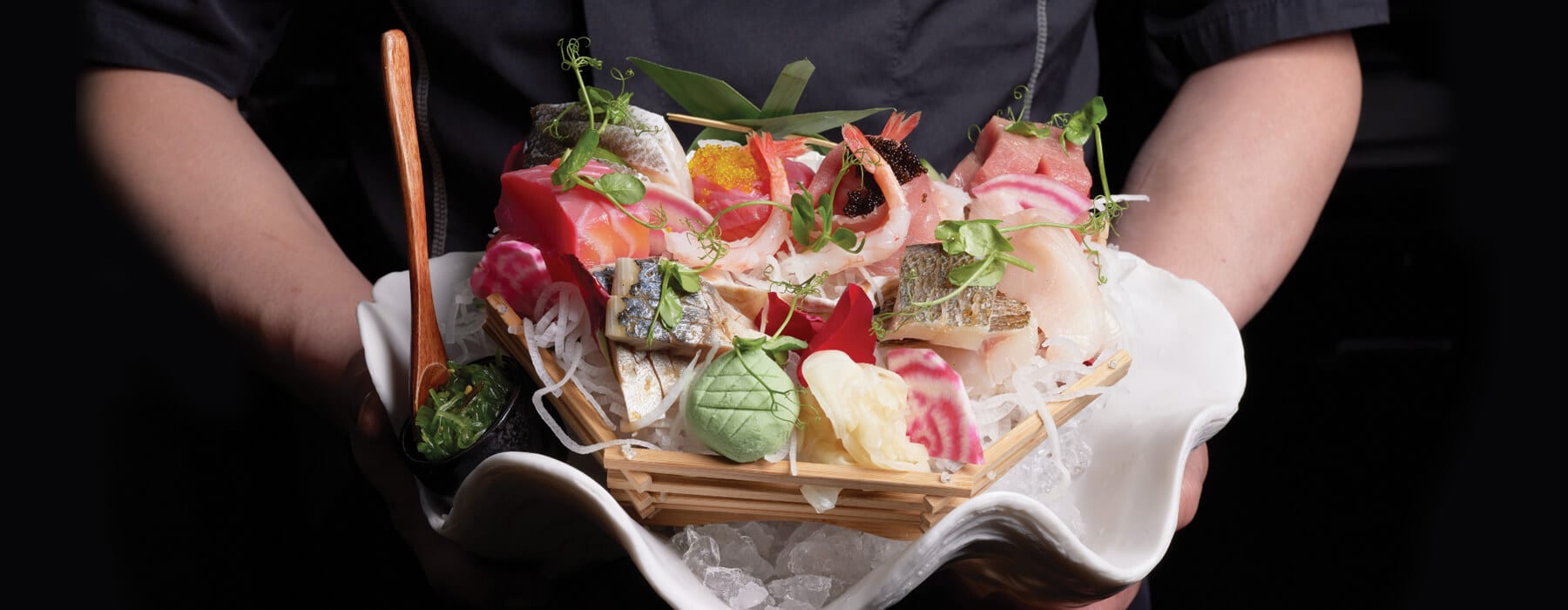 A sashimi platter dressed with flowers and ice