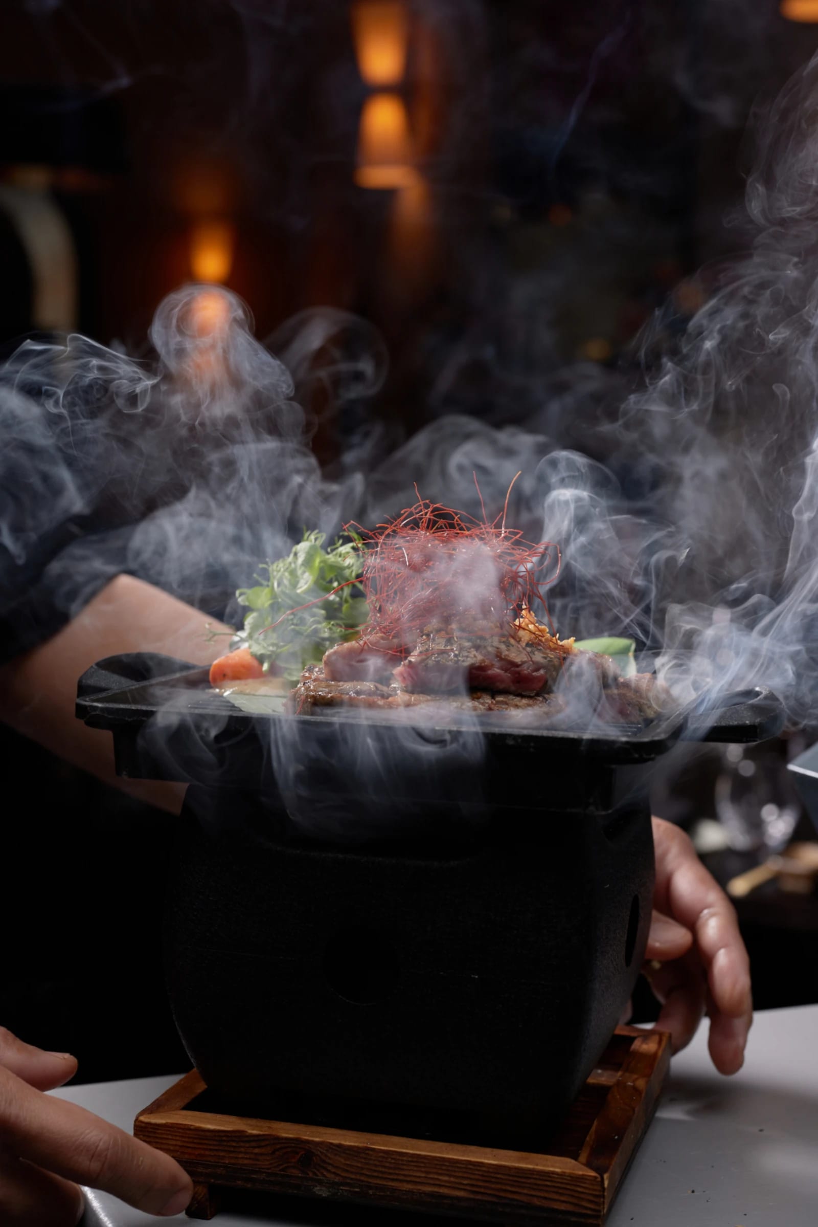 A server carrying a stone bowl pouring with smoke