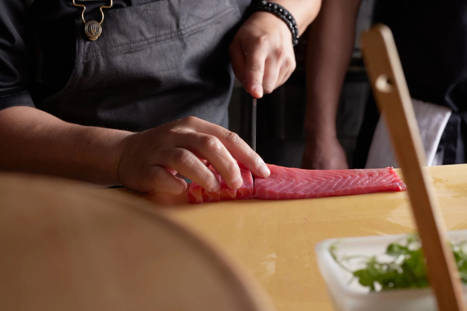 A chef's hands carving a whole tuna loin